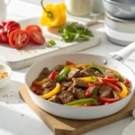 Pepper steak recipe in white skillet with bell peppers and sauce